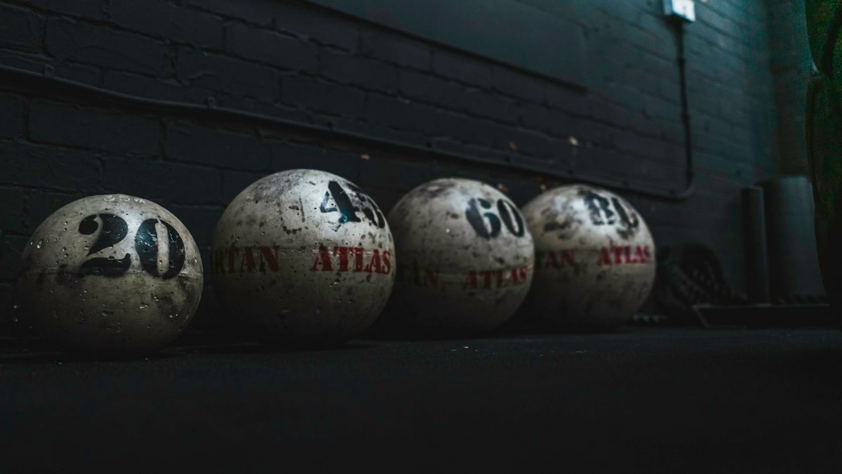 Sports balls on a cart in a gym.